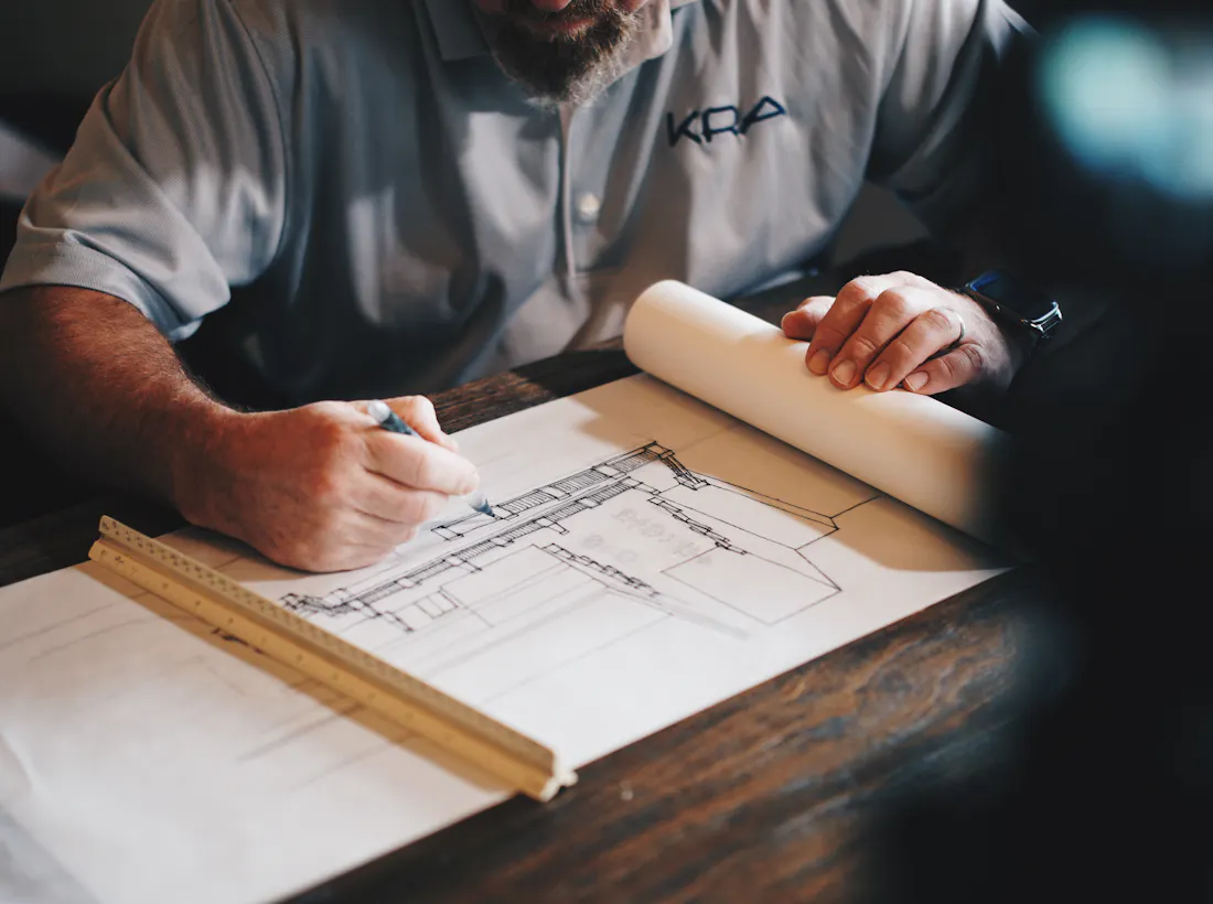 Hands reviewing architectural plans with a scale ruler